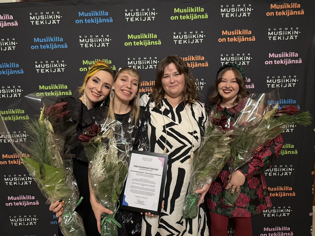 Neljä hymyilevää naista vierekkäin, kaikilla on kukat ja yhdellä diplomi kädessä.